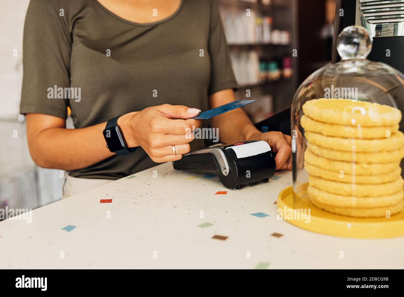 Vista laterale di una donna irriconoscibile che paga con la tecnologia NFC su carta di credito nel bar Foto Stock