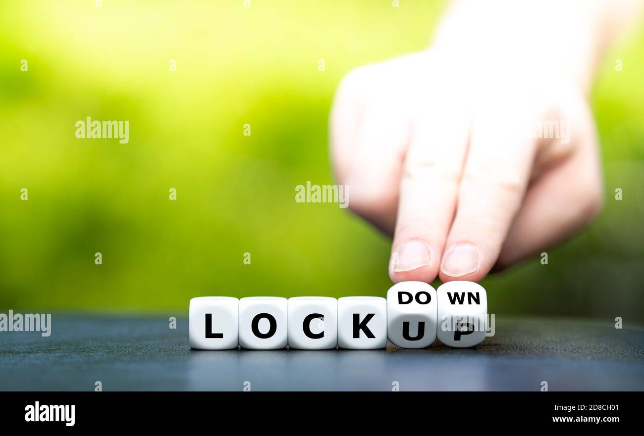 Blocco o blocco? La mano trasforma i dadi e cambia l'espressione "LOCK up" in "lock down". Foto Stock