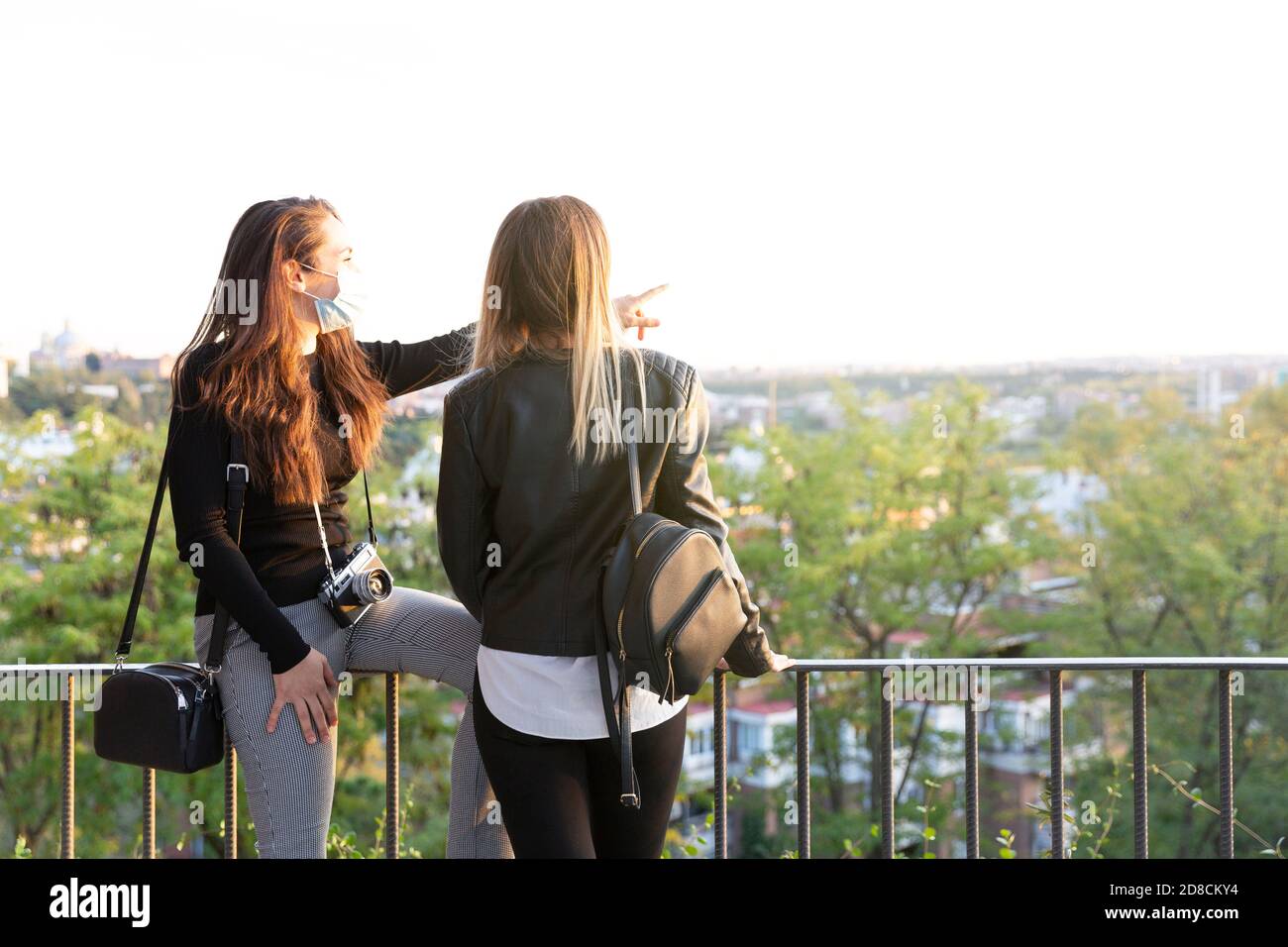 Due ragazze che guardano la città da un punto di vista. Indossano maschere facciali. Spazio per il testo. Foto Stock