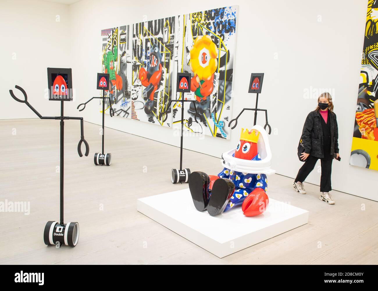 Un visitatore guarda le opere d'arte insieme ai robot telecomandati in un'anteprima stampa della mostra "Philip Colbert: Lobsteropolis" alla Saatchi Gallery di Londra, che offre al pubblico la possibilità di vedere le opere d'arte in situ o tramite i robot comodamente a casa propria. Foto Stock