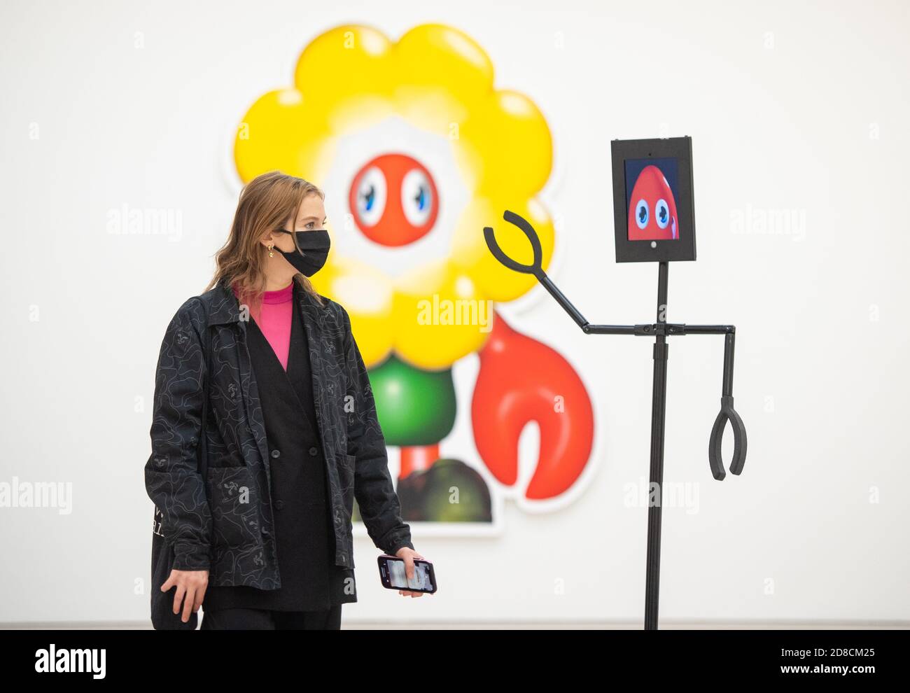 Un visitatore guarda le opere d'arte insieme ai robot telecomandati in un'anteprima stampa della mostra "Philip Colbert: Lobsteropolis" alla Saatchi Gallery di Londra, che offre al pubblico la possibilità di vedere le opere d'arte in situ o tramite i robot comodamente a casa propria. Foto Stock