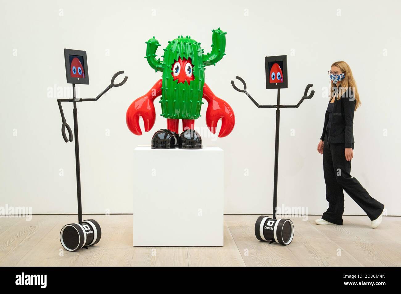 Un visitatore guarda le opere d'arte insieme ai robot telecomandati in un'anteprima stampa della mostra "Philip Colbert: Lobsteropolis" alla Saatchi Gallery di Londra, che offre al pubblico la possibilità di vedere le opere d'arte in situ o tramite i robot comodamente a casa propria. Foto Stock