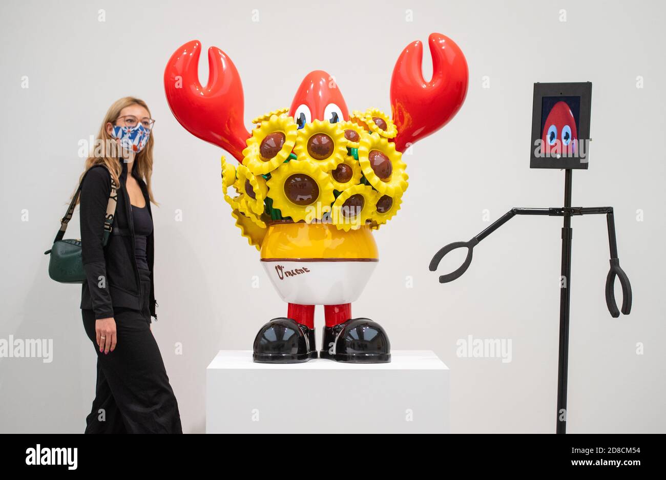 Un visitatore guarda le opere d'arte insieme ai robot telecomandati in un'anteprima stampa della mostra "Philip Colbert: Lobsteropolis" alla Saatchi Gallery di Londra, che offre al pubblico la possibilità di vedere le opere d'arte in situ o tramite i robot comodamente a casa propria. Foto Stock