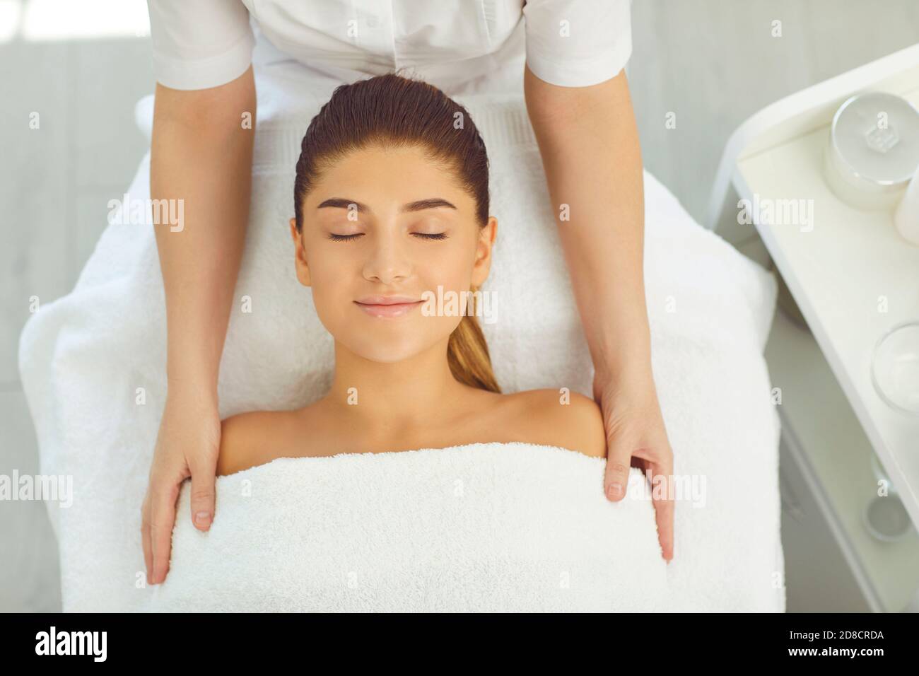 Giovane donna caucasica che riceve massaggio di testa, collo e spalle al centro benessere. Foto Stock
