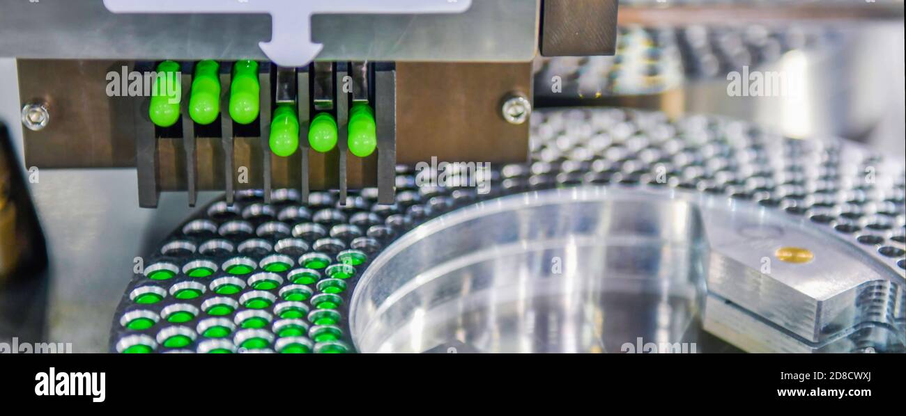 Linea di produzione di pillole di medicina a capsula verde, concetto farmaceutico industriale. Foto Stock