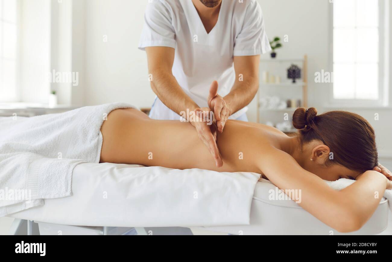 Massaggiatore che fa massaggio alla schiena per la giovane donna usando la tecnica di Tapotement per alleviare la tensione muscolare Foto Stock