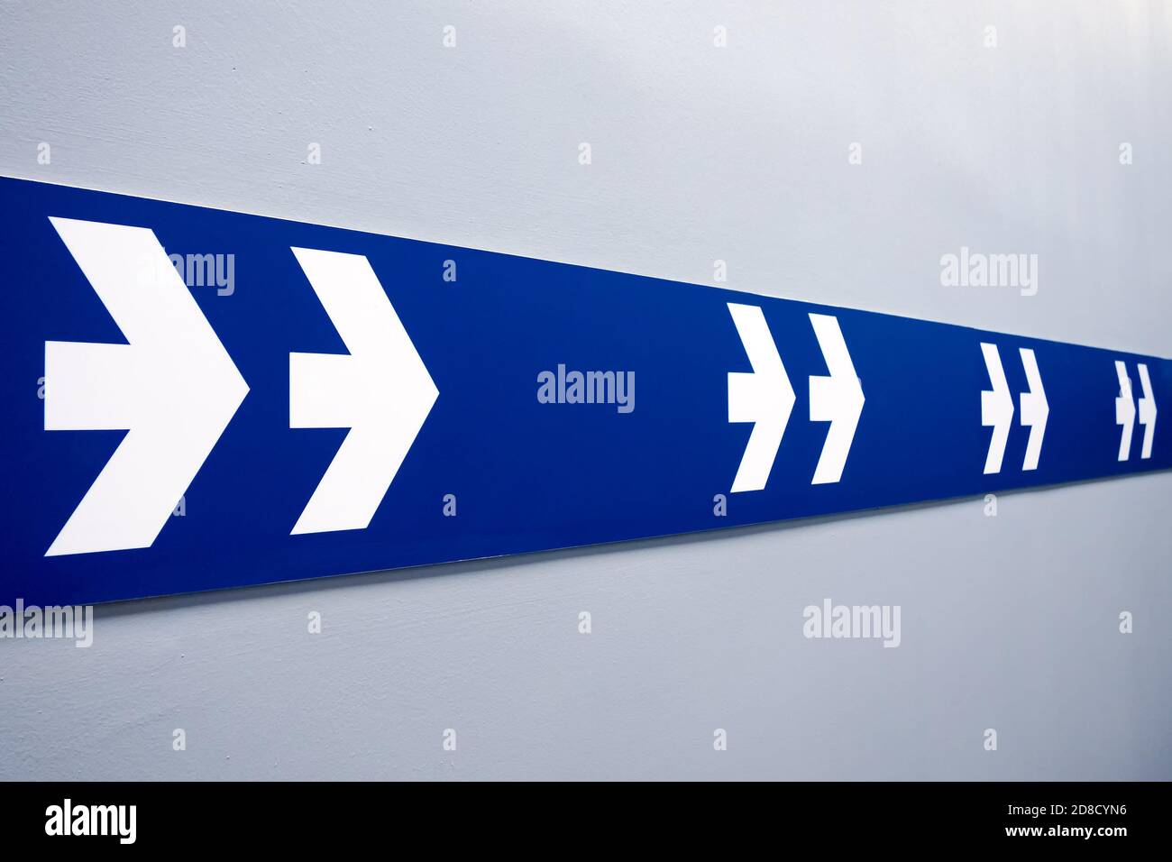 due frecce bianche sulla striscia blu che indicano l'uscita Foto Stock