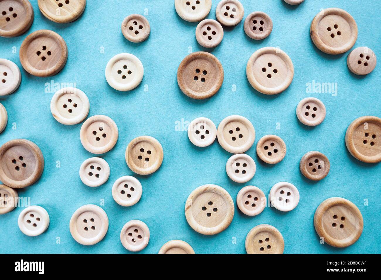 molti grandi e piccoli bottoni di legno beige su sfondo blu Foto Stock