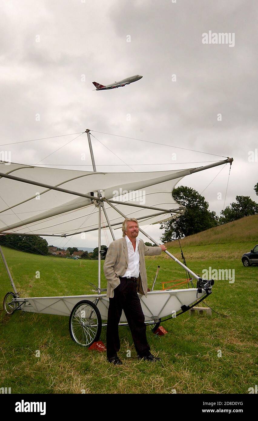 Richard Branson accanto a una replica del aliante di Sir George Cayley, con un Virgin Atlantic Boeing 747 (G-VAST) che fa un basso cavalcavia, prima di r Foto Stock