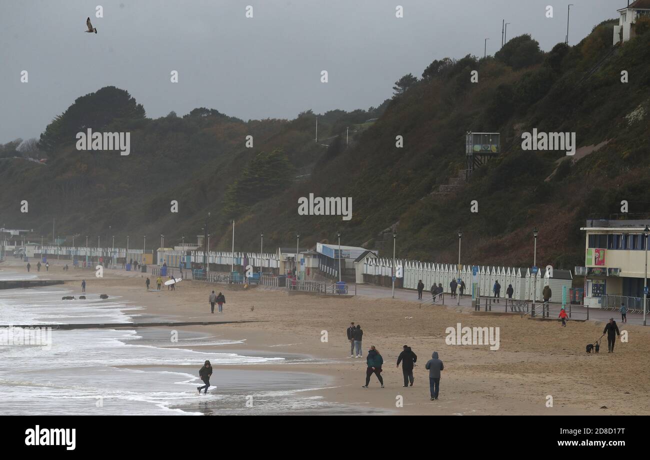 La gente si fa strada lungo la spiaggia di Bournemouth a Dorset. Il Met Office ha avvertito che i downpour torrenziali sono previsti per portare 'infuori' in tutto il Regno Unito con grandi onde, pioggia pesante, forti galee e potenziali inondazioni fluviali che colpiscono la costa occidentale dell'Inghilterra, gran parte del Galles e parti della Scozia da giovedì. Foto Stock