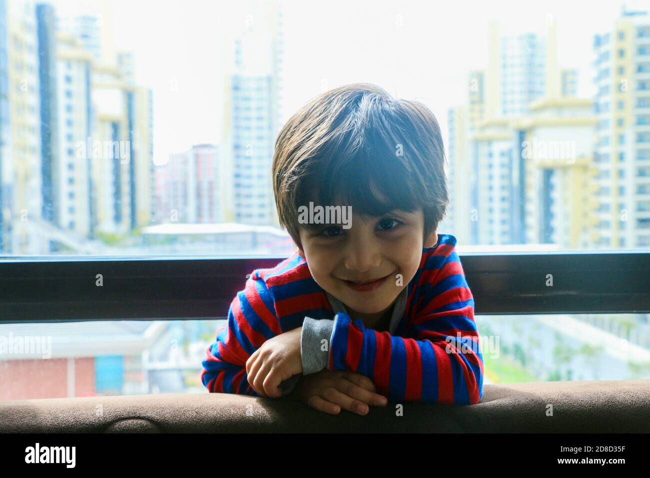 Un bambino si affaccia sul giardino dal balcone. Foto Stock