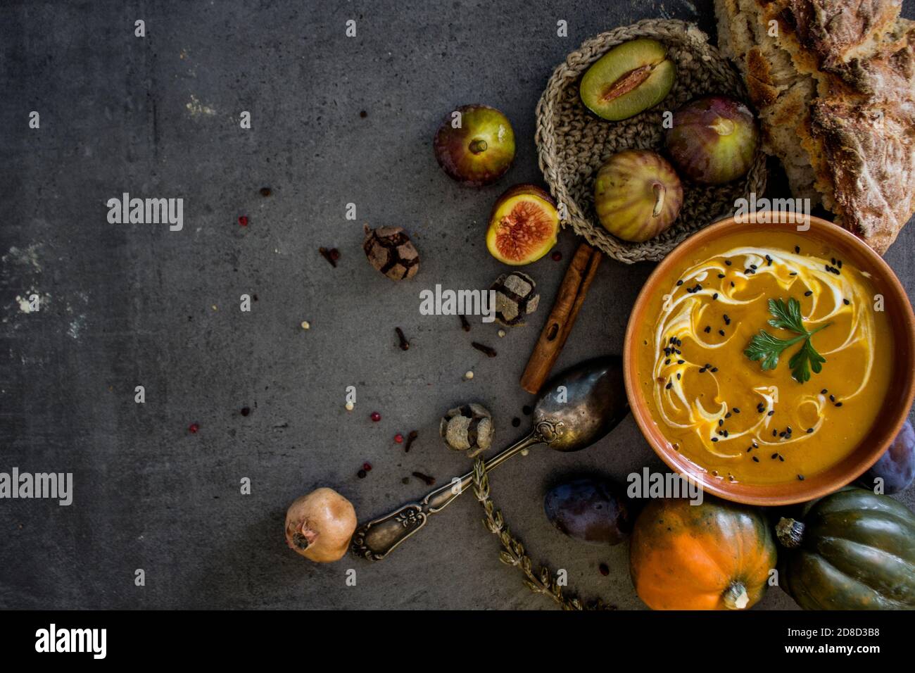 Zuppa di zucca con pane appena sfornato e cucchiaio d'argento su tavola grigia. Foto dall'alto del pasto vegano. Concetto di alimentazione sana. Foto Stock