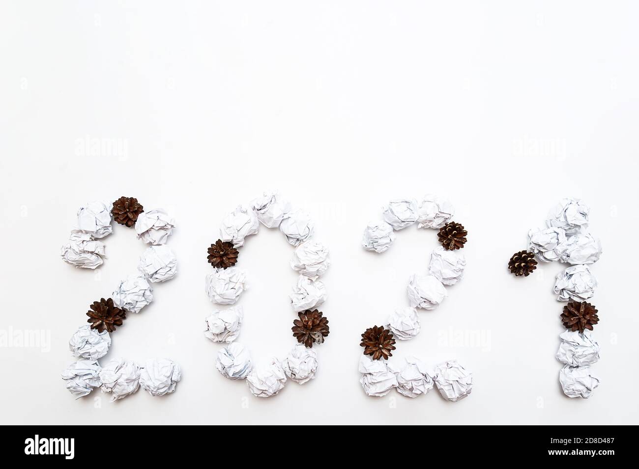 2021 figure da sminuzzate in una sfera di carta bianca, coni di pino e stelle su uno sfondo bianco. Concetto di anno nuovo Foto Stock