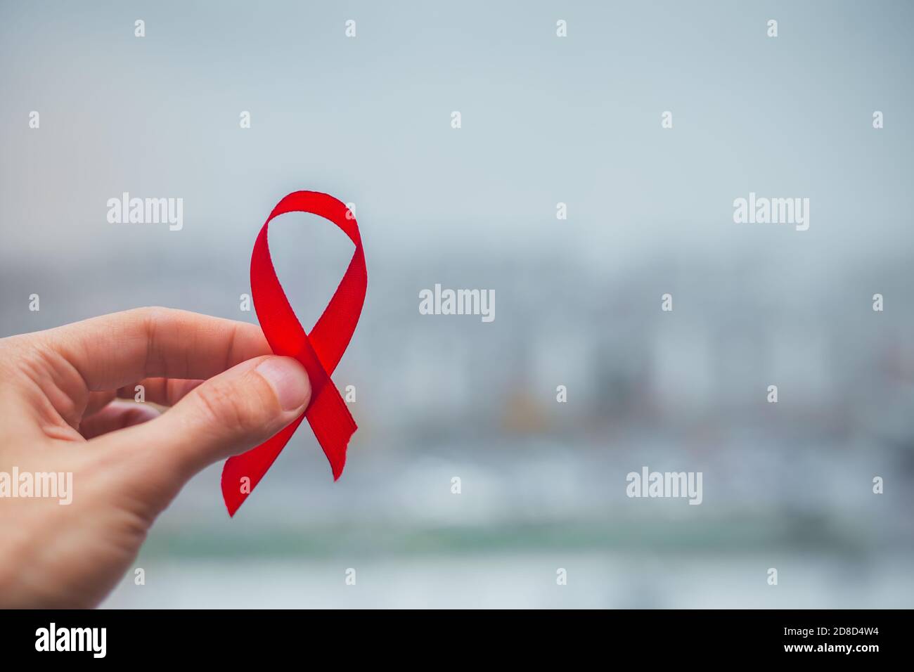 Nastro rosso fiocco simbolo HIV, AIDS cancro consapevolezza con ombre, studio girato isolato su sfondo rosso, medicina sanitaria concetto, Giornata Mondiale dell'AIDS Foto Stock