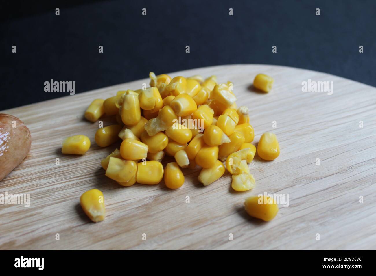Colazione, pranzo o cena, mais dolce e salsiccia alla griglia La salsiccia si trova su un vassoio di legno di supporto per asse su un sfondo nero scuro dello spazio di copia Foto Stock
