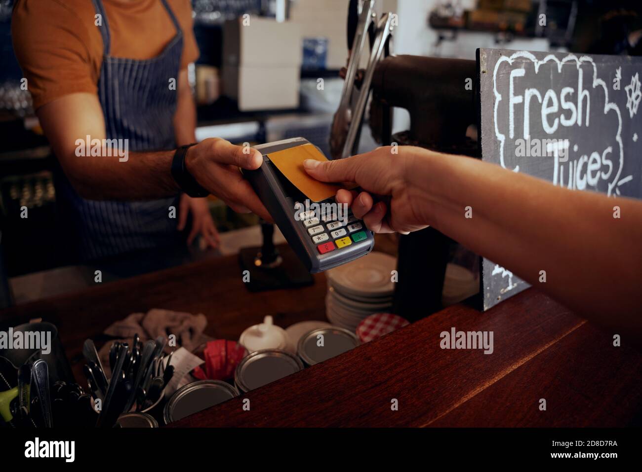 Mani femminili che tengono la carta contro la macchina di pagamento nfs per fare pagamento per acquisto in caffetteria Foto Stock