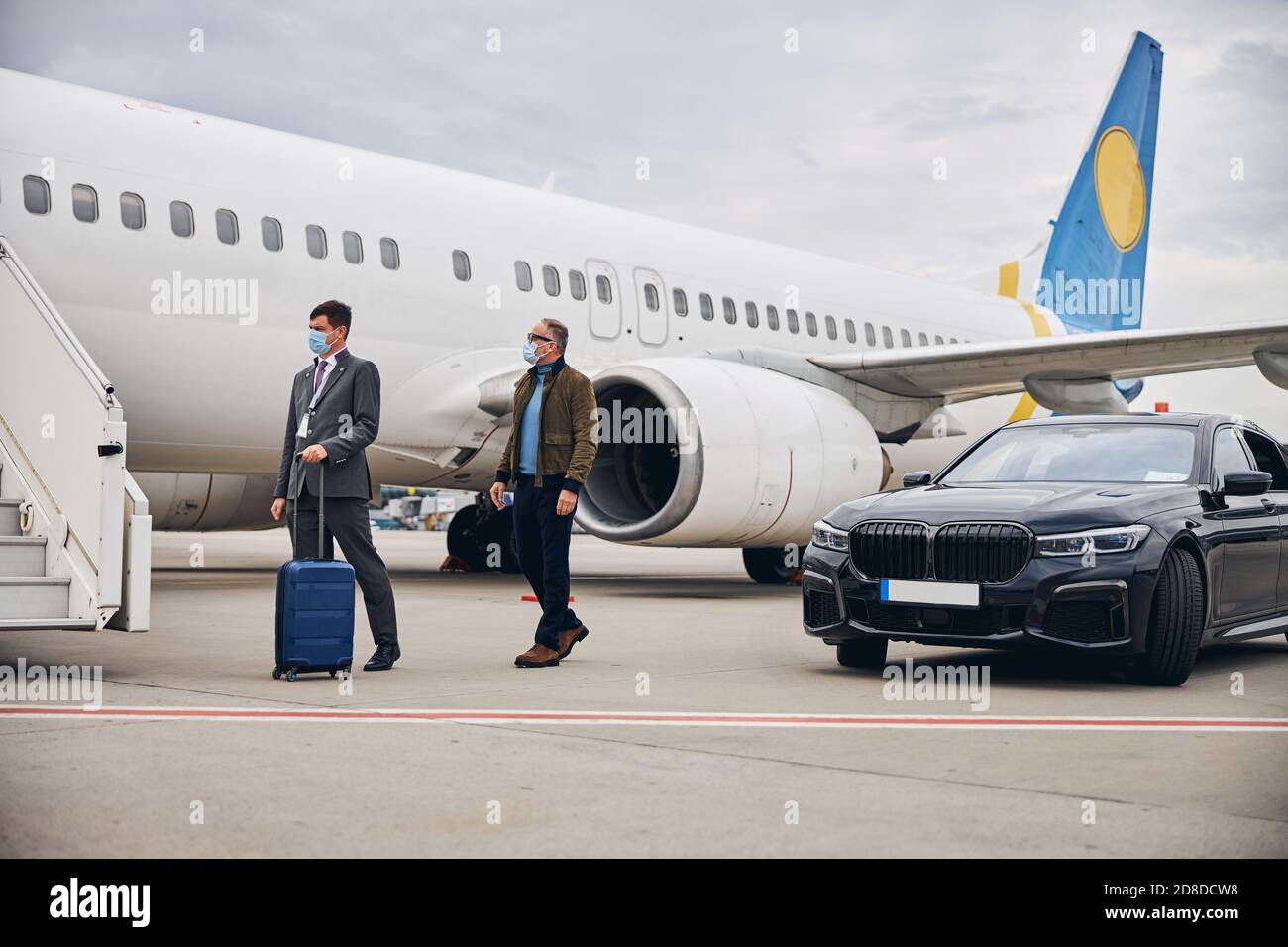 Uomo d'affari accompagnato dall'operaio dell'aeroporto all'aeromobile Foto Stock