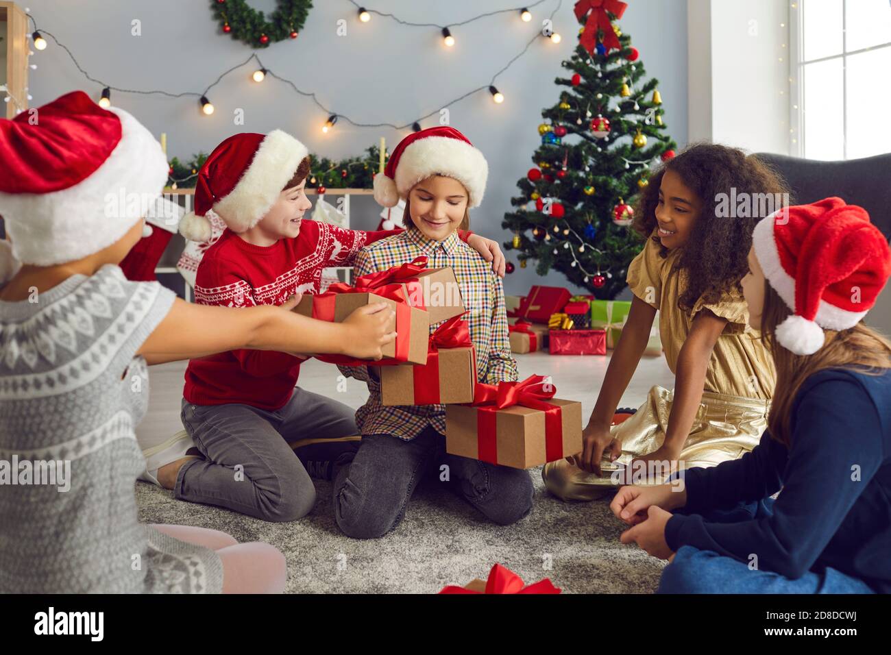 Ragazza piccola felice che ottiene i lotti dei regali di Natale da lei amici gentili o fratelli Foto Stock