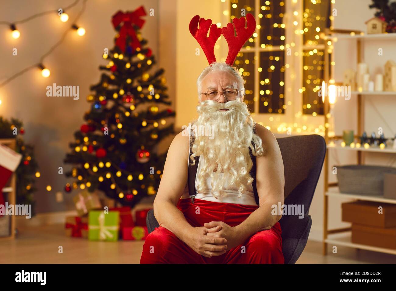 Babbo Natale serio indossando antlers renna che si rilassano in poltrona dopo lunga giornata di lavoro Foto Stock