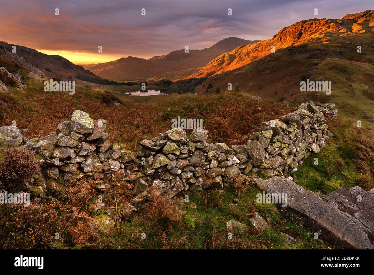 Splendida alba con prima luce sulle cime delle montagne su Side Pike nel Lake District, Regno Unito. Un vecchio muro di pietra può essere visto in primo piano. Foto Stock