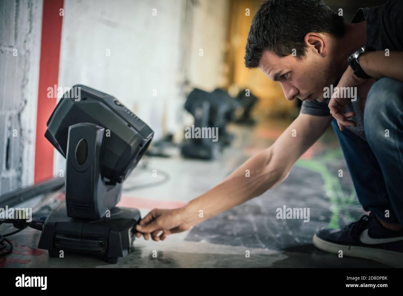 Tecnico di illuminazione teatrale ingegnere elettrico regolazione del fuoco degli elementi di illuminazione backstage. Faretti nel teatro. Dietro la scena Foto Stock