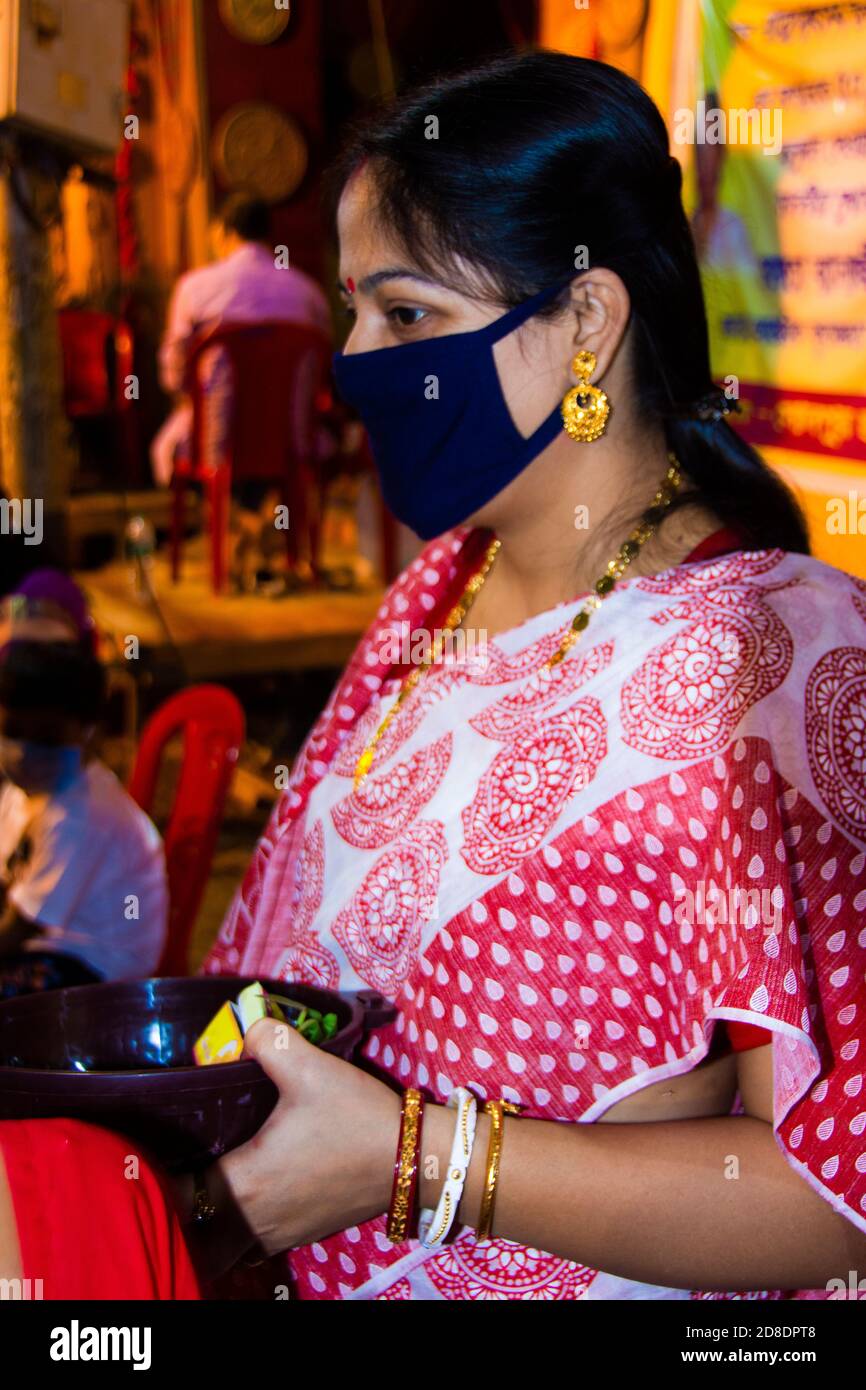 Bella donna in un sari bengalese e muschio che tiene pooja thali a Kolkata Durga puja pandel Foto Stock