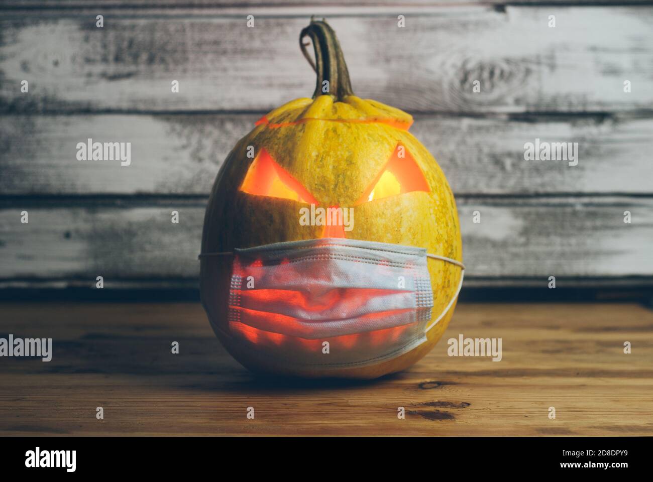 Cupo Jack-o-lanterna in una maschera medica su uno sfondo di legno Foto Stock