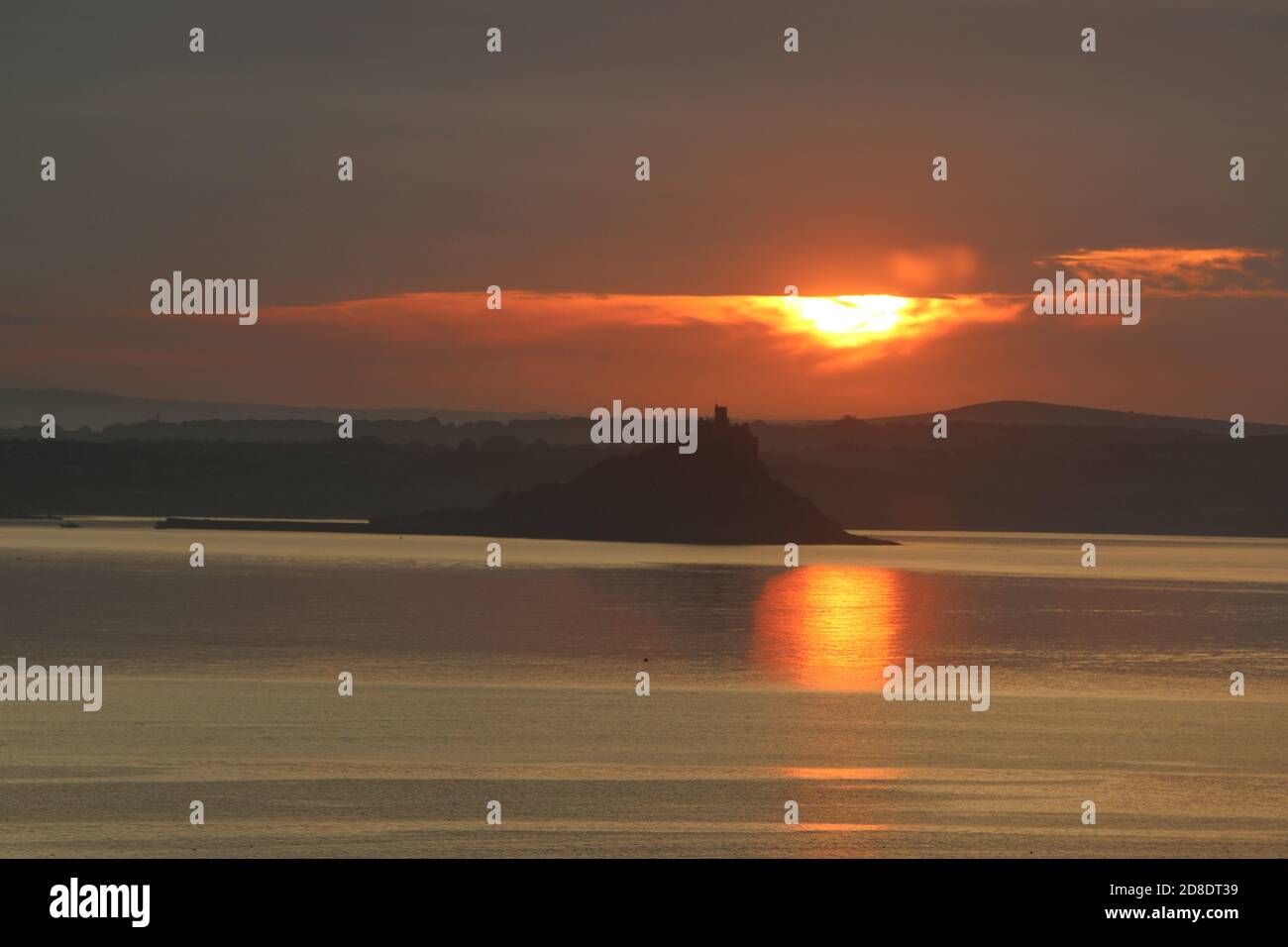 Monte di San Michele, Penzance, che si affaccia sul mare di Mount's Bay con il sole arancione che si erge dietro di esso e si riflette nell'acqua Foto Stock