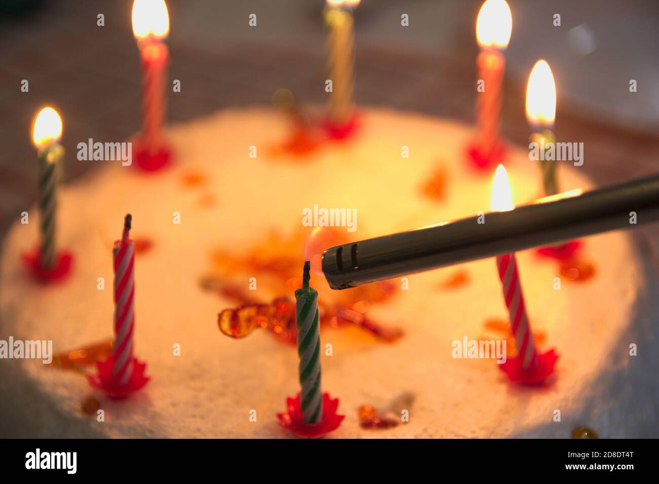 Closeup di una torta di anniversario decorata con candele che sono essere illuminato con un accendisigari Foto Stock