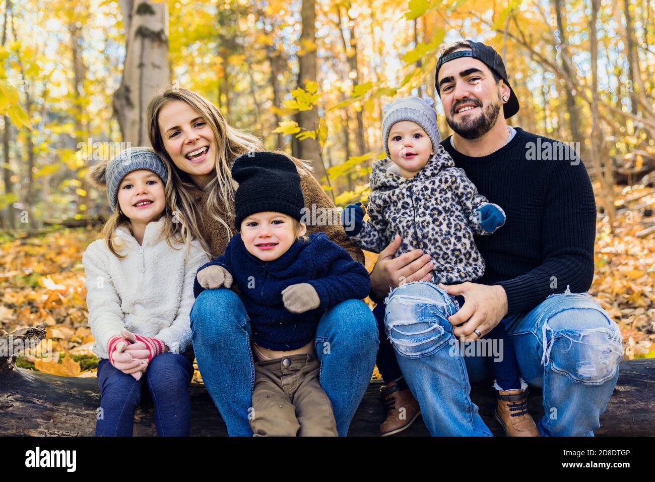 Famiglia Gruppo relax all'aperto in autunno Paesaggio sedersi su log Foto Stock