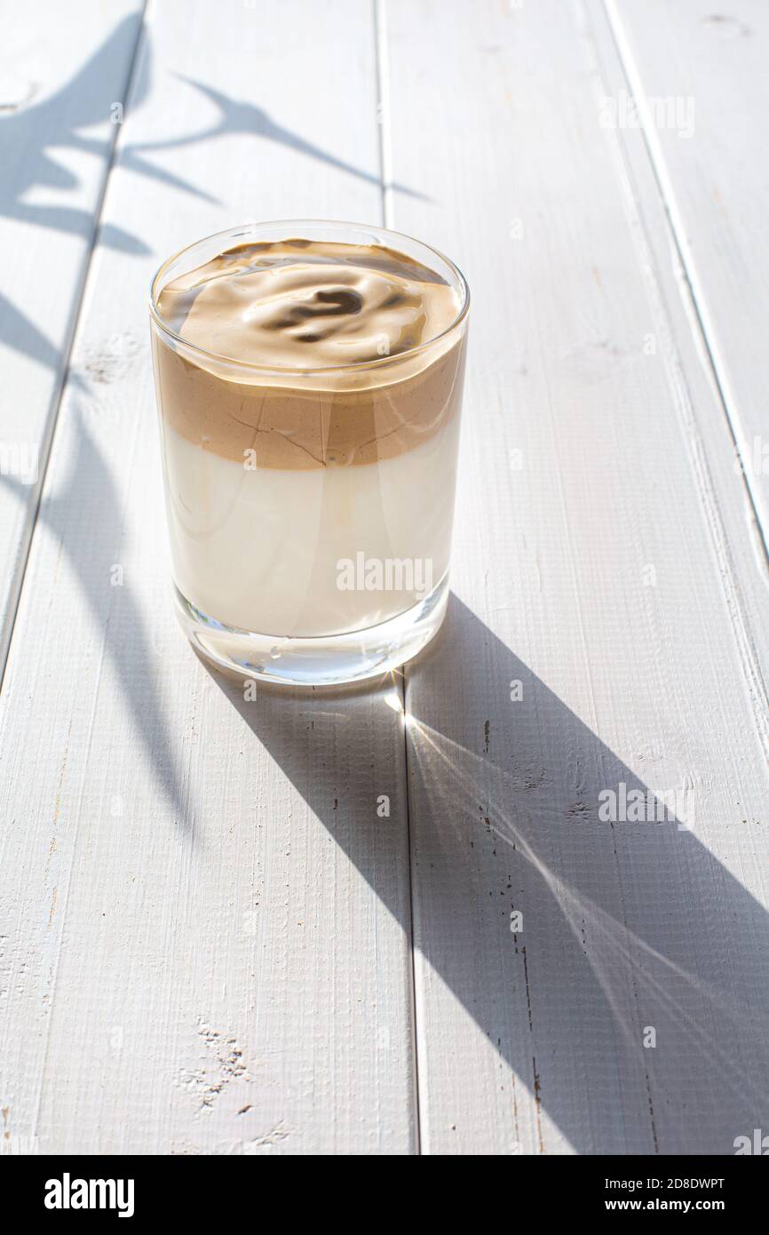 Bevanda tradizionale coreana con caffeina, caffè dalgona in un bicchiere trasparente su sfondo bianco. Latte e caffè montato. Un rinvigorente br Foto Stock