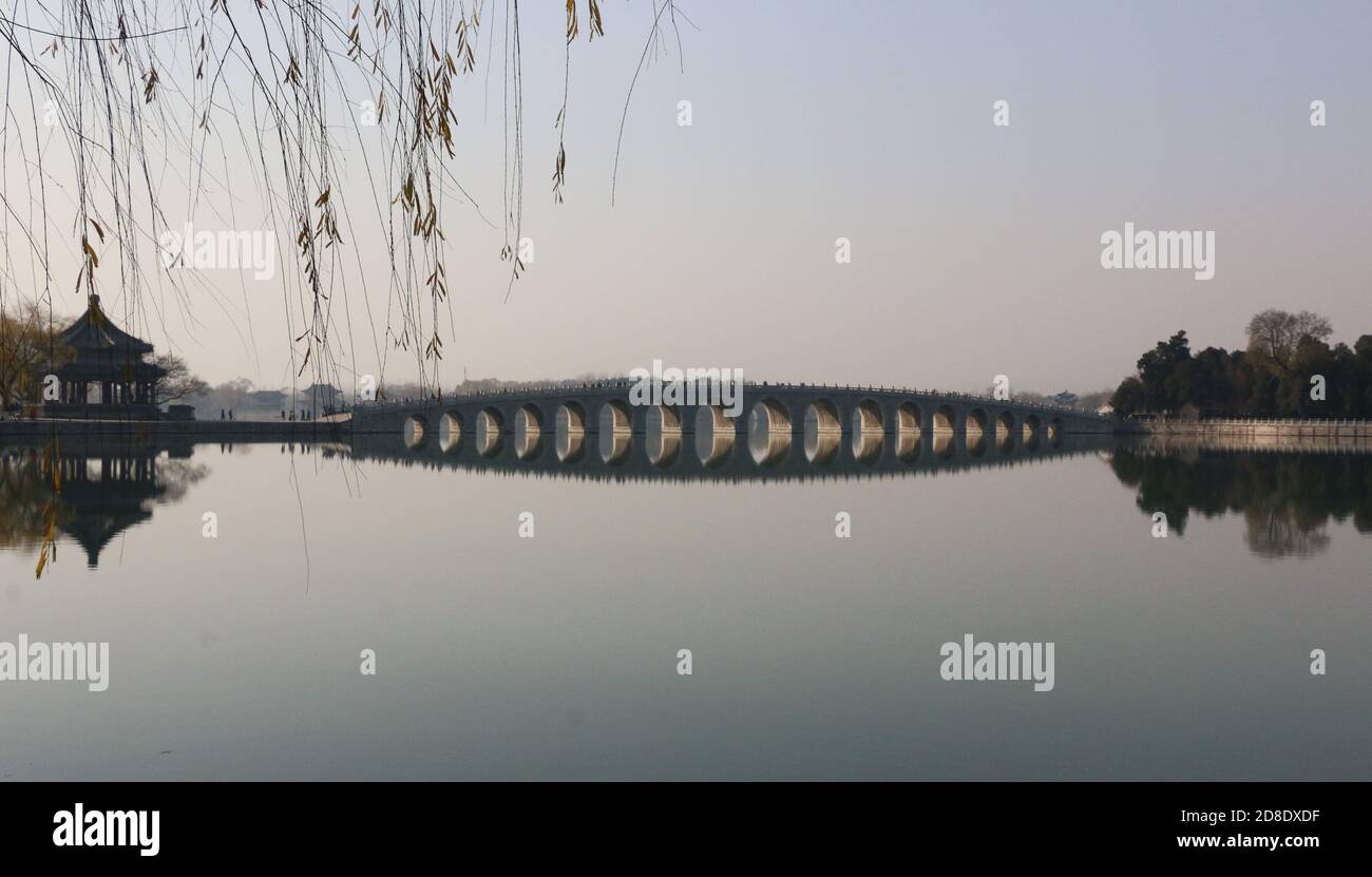 Ponte a diciassette archi sul lago Kunming al Palazzo Estivo di Pechino, incorniciato da rami salici e con spazio per la copia Foto Stock