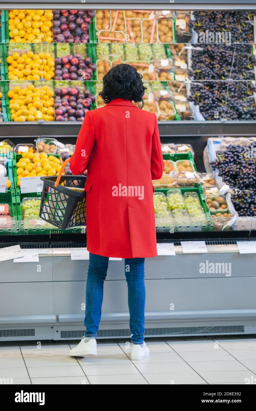 Al supermercato: La donna sceglie frutta biologica nella sezione prodotti freschi del negozio. Foto vista posteriore. Foto Stock
