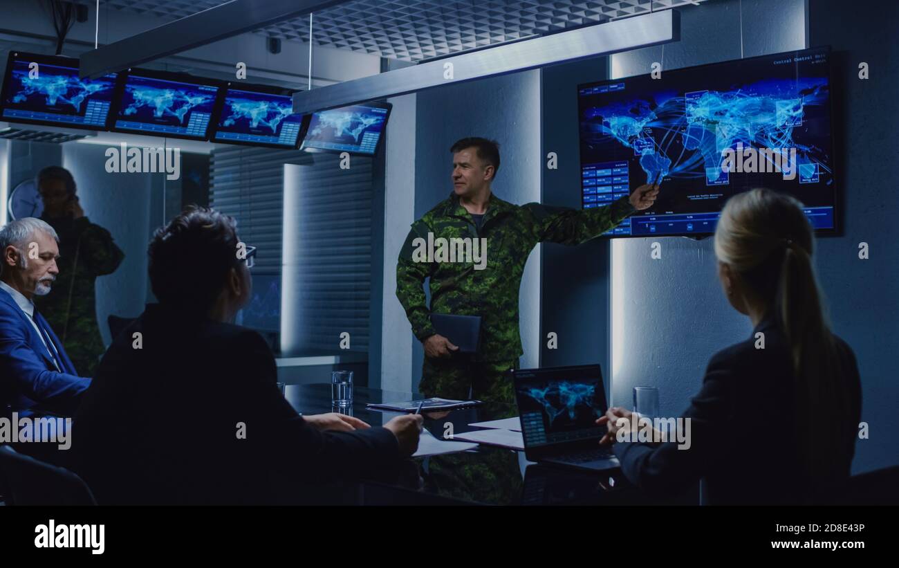 High-Ranking Military Man tiene un briefing a un team di agenti governativi e politici, mostra le riprese di sorveglianza satellitare. Foto Stock