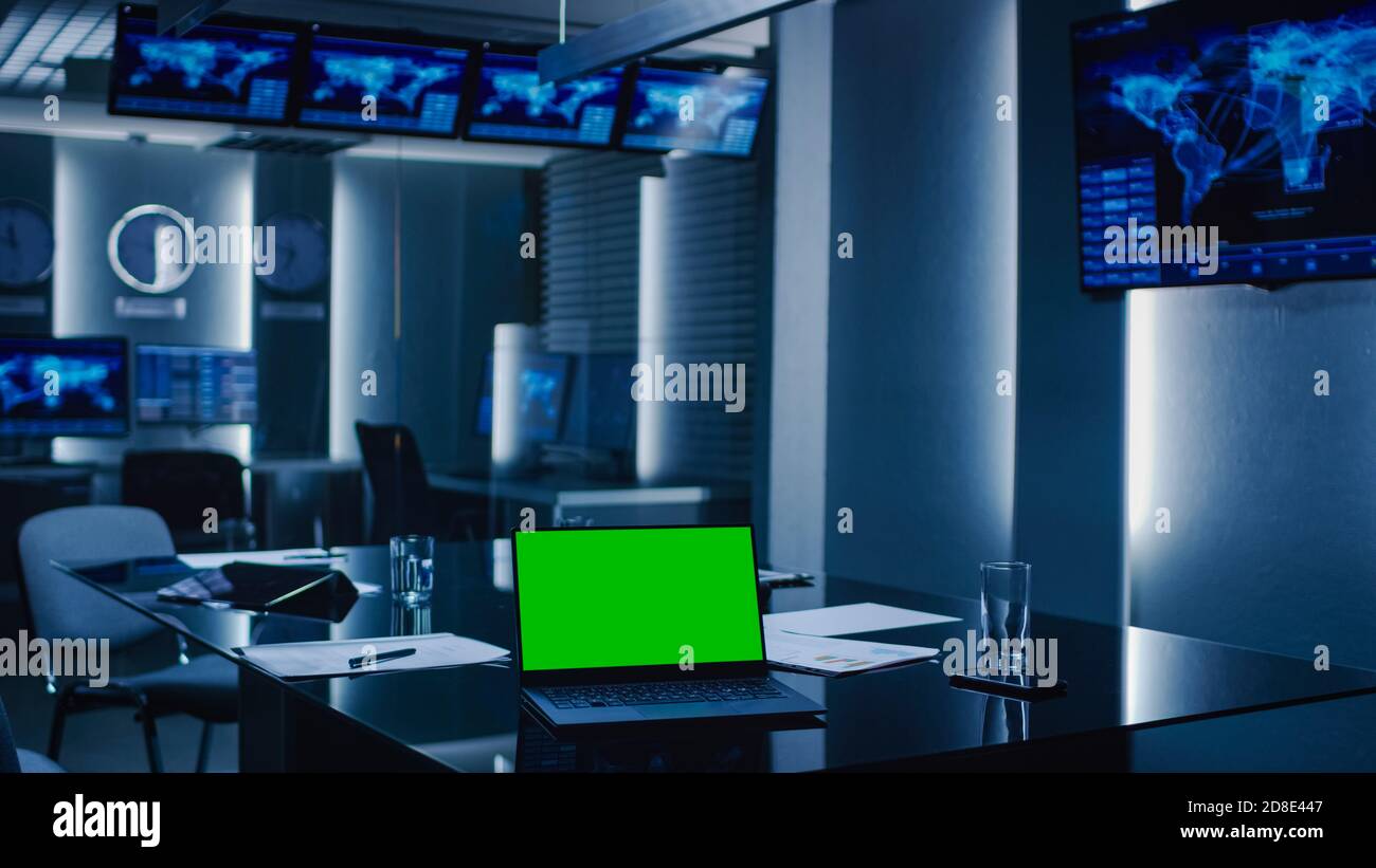 Immagine della sala di monitoraggio del controllo del sistema. Centro operativo di emergenza governativo vuoto. Sul portatile da tavolo che mostra la schermata di mock-up verde. Foto Stock
