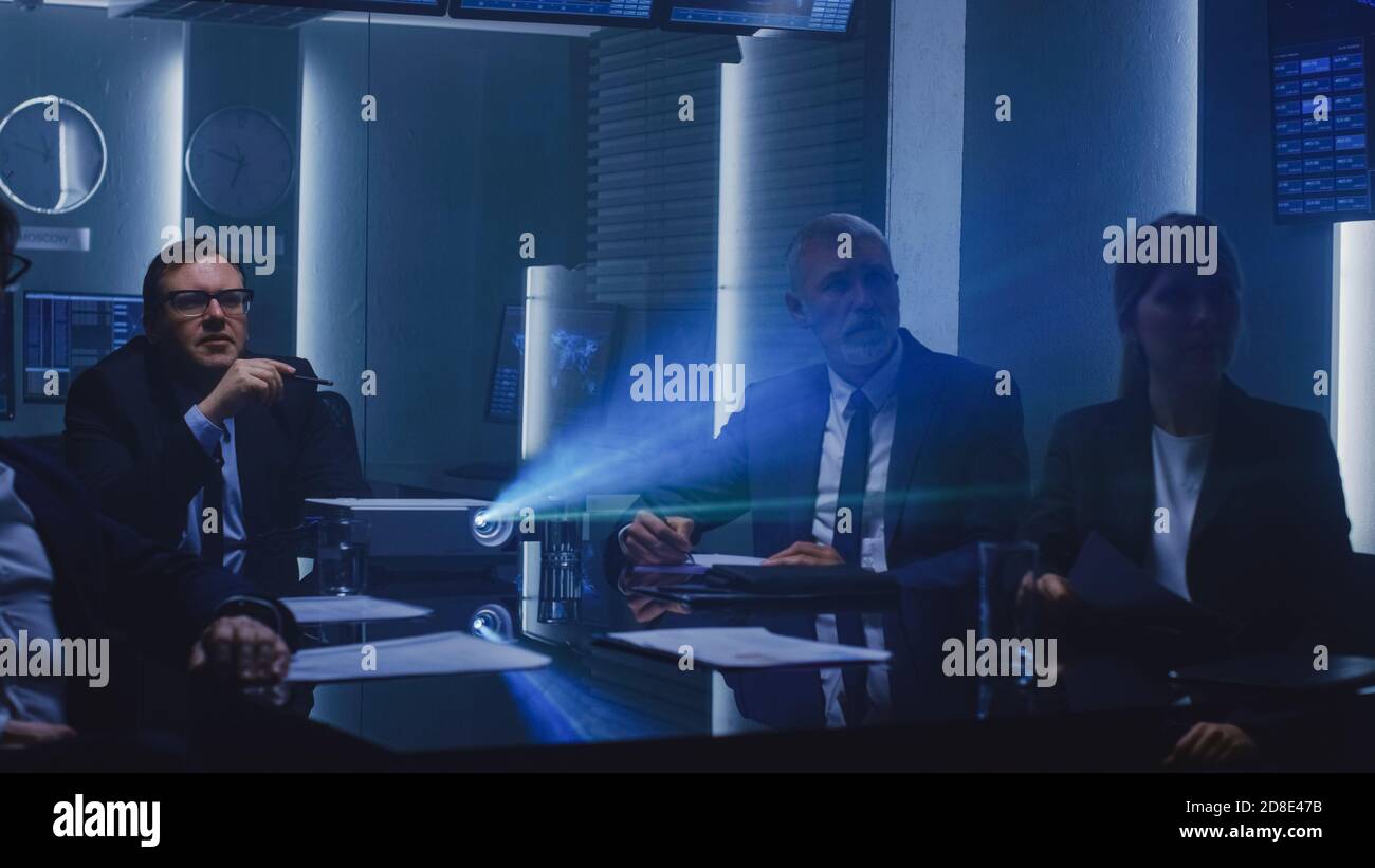 Funzionari governativi, militari e dirigenti aziendali di alto livello che guardano la presentazione nella Sala conferenze. Proiettore di lavoro sul tavolo. Foto Stock