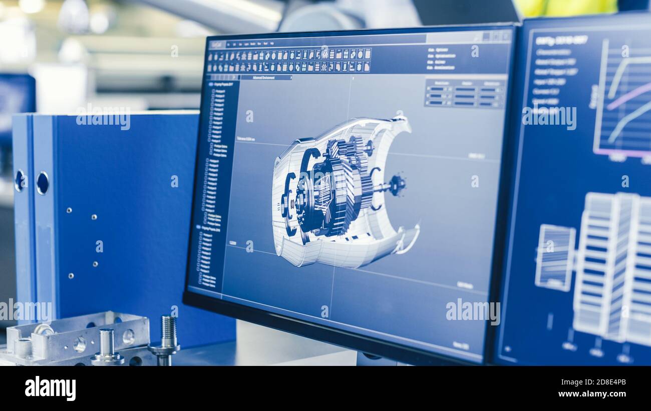 Primo piano del modello CAD 3D del motore visualizzato sullo schermo del computer. In background Manufacturing Factory con persone che lavorano. Foto Stock