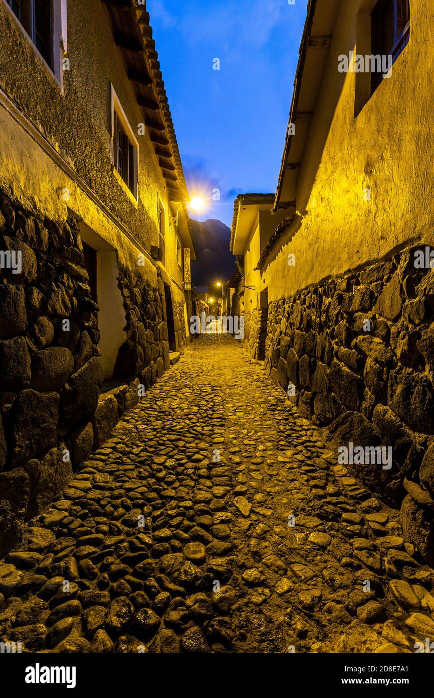 Strada di ciottoli e mura Inca al crepuscolo, Ollantaytambo, Perù Foto Stock