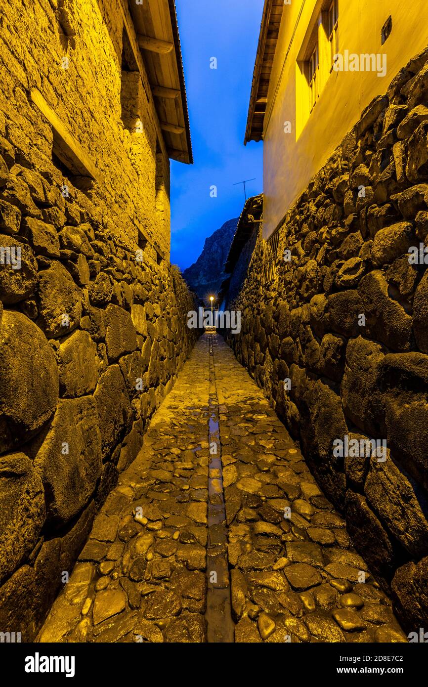 Strada di ciottoli e mura Inca al crepuscolo, Ollantaytambo, Perù Foto Stock