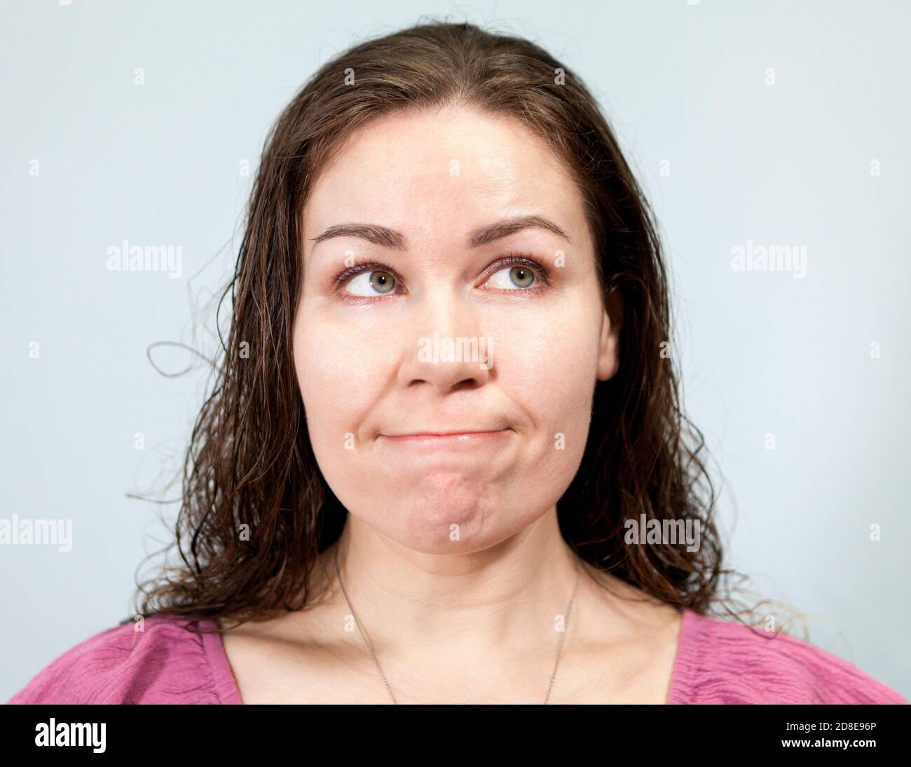 Nervosismo e ansia, labbra pursate e uno sguardo al lato, ritratto di donna su sfondo grigio, serie di emozioni Foto Stock