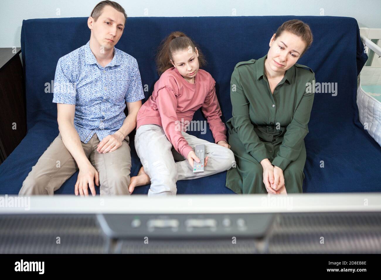 Noiosa famiglia caucasica seduta sul divano passare il tempo insieme guardando la televisione, la gente che rimane a casa Foto Stock