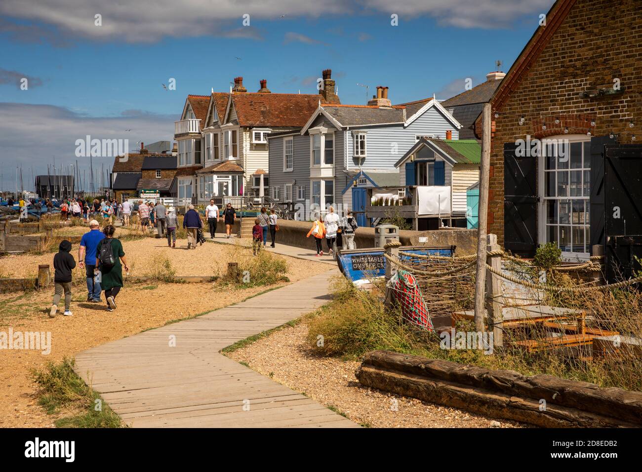 Regno Unito, Kent, Whitstable, Reeves Beach, visitatori sulla via delle mura di mare presso le capanne dei pescatori Foto Stock