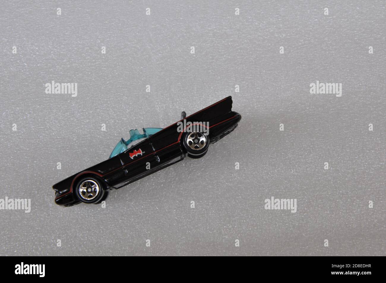 Auto giocattolo Batman in miniatura, vista laterale con ruote, porta e lato della vettura, a fuoco differenziale con spazio di copia, sfondo bianco Foto Stock
