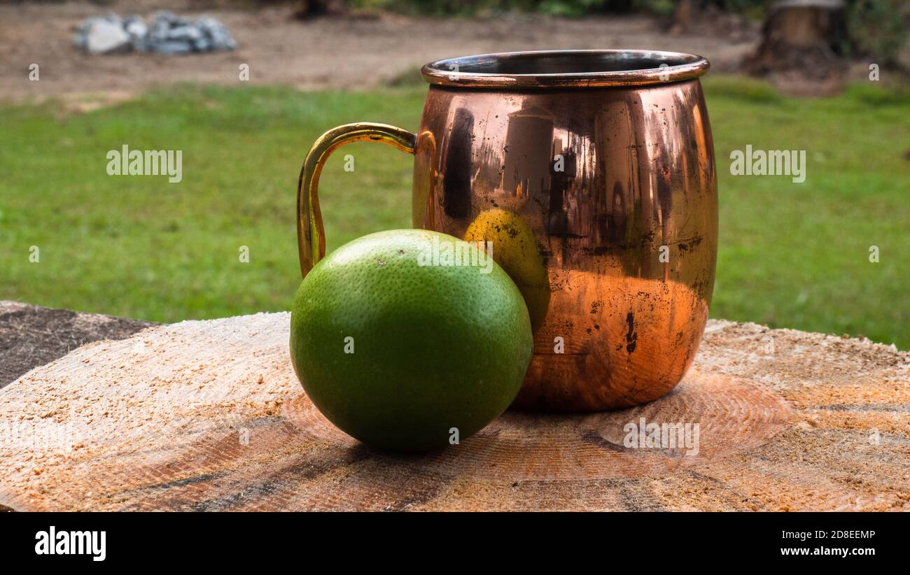 Tazza di rame seduta accanto ad un calce su legno naturale piastra Foto Stock
