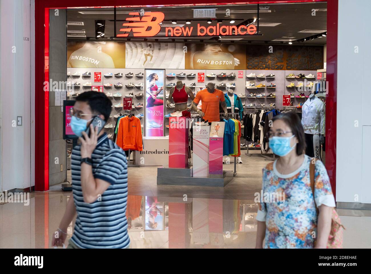 Hong Kong, Cina. 8 Ott 2020. Le persone che indossano maschere facciali camminano oltre un marchio americano di calzature New Balance negozio e logo visto a Hong Kong. Credit: Budrul Chukrut/SOPA Images/ZUMA Wire/Alamy Live News Foto Stock