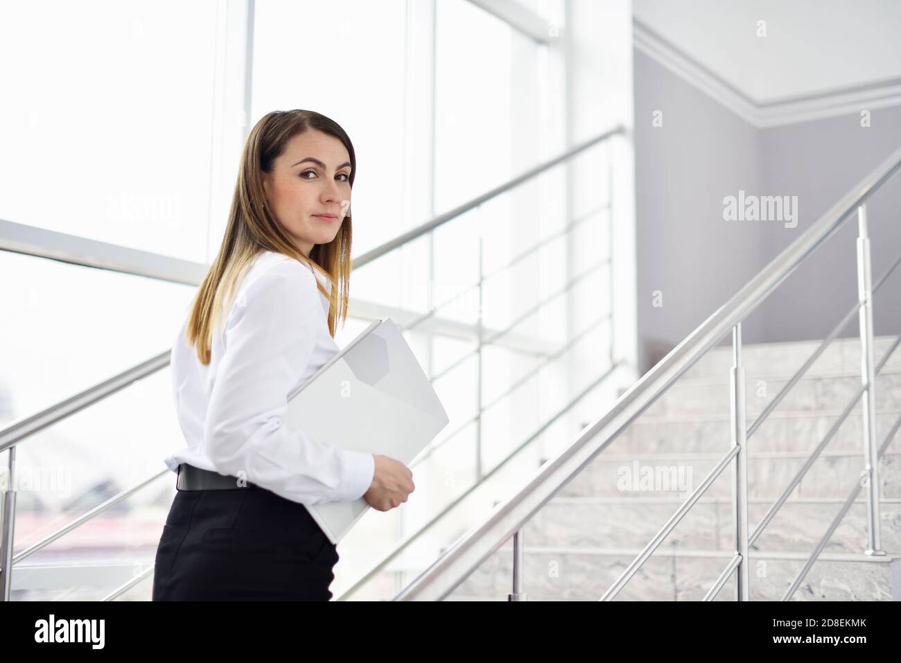 Donna di mezza età che cammina le scale e porta un curriculum per ottenere un lavoro Foto Stock