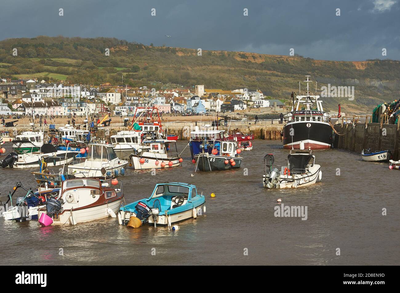 Lyme Regis, Dorset e barche da pesca rifugio nel porto sotto i cieli tempestosi autunnali. Foto Stock