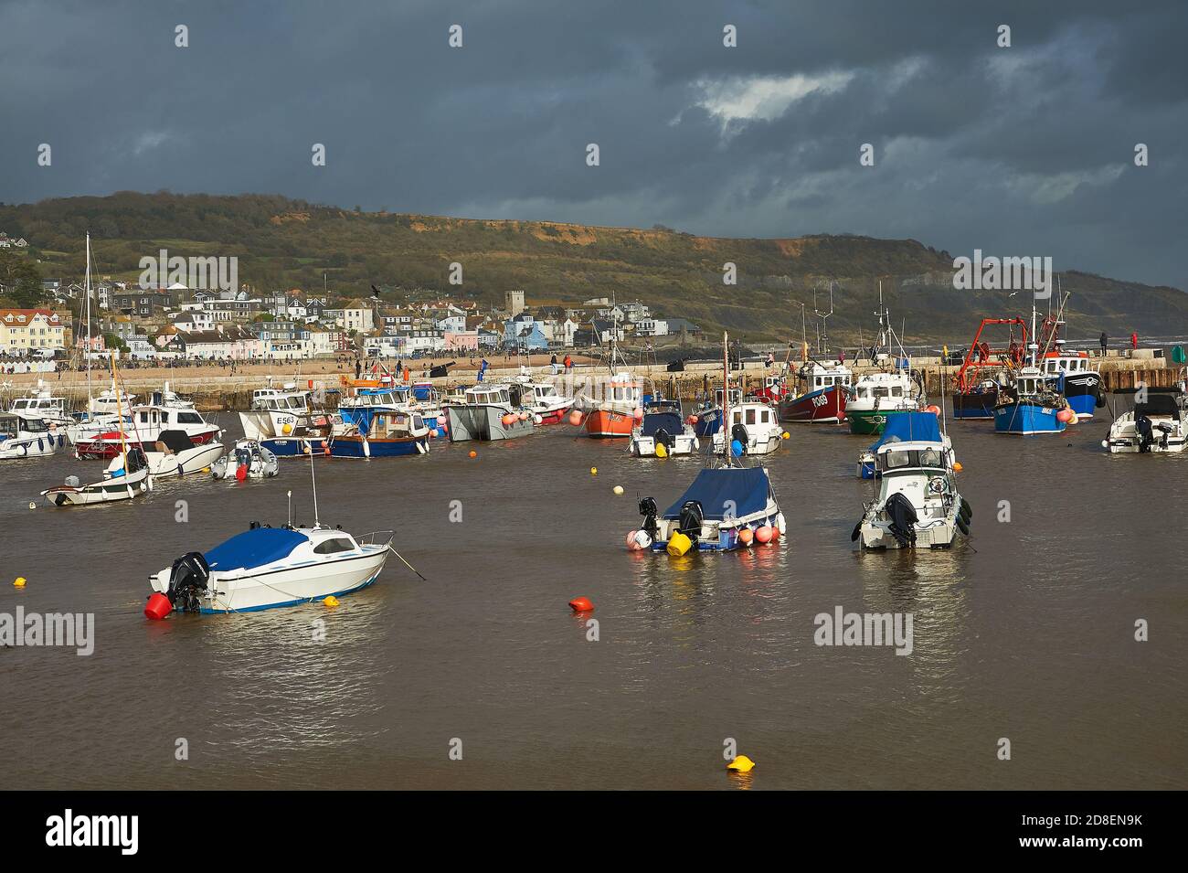 Lyme Regis, Dorset e barche da pesca rifugio nel porto sotto i cieli tempestosi autunnali. Foto Stock