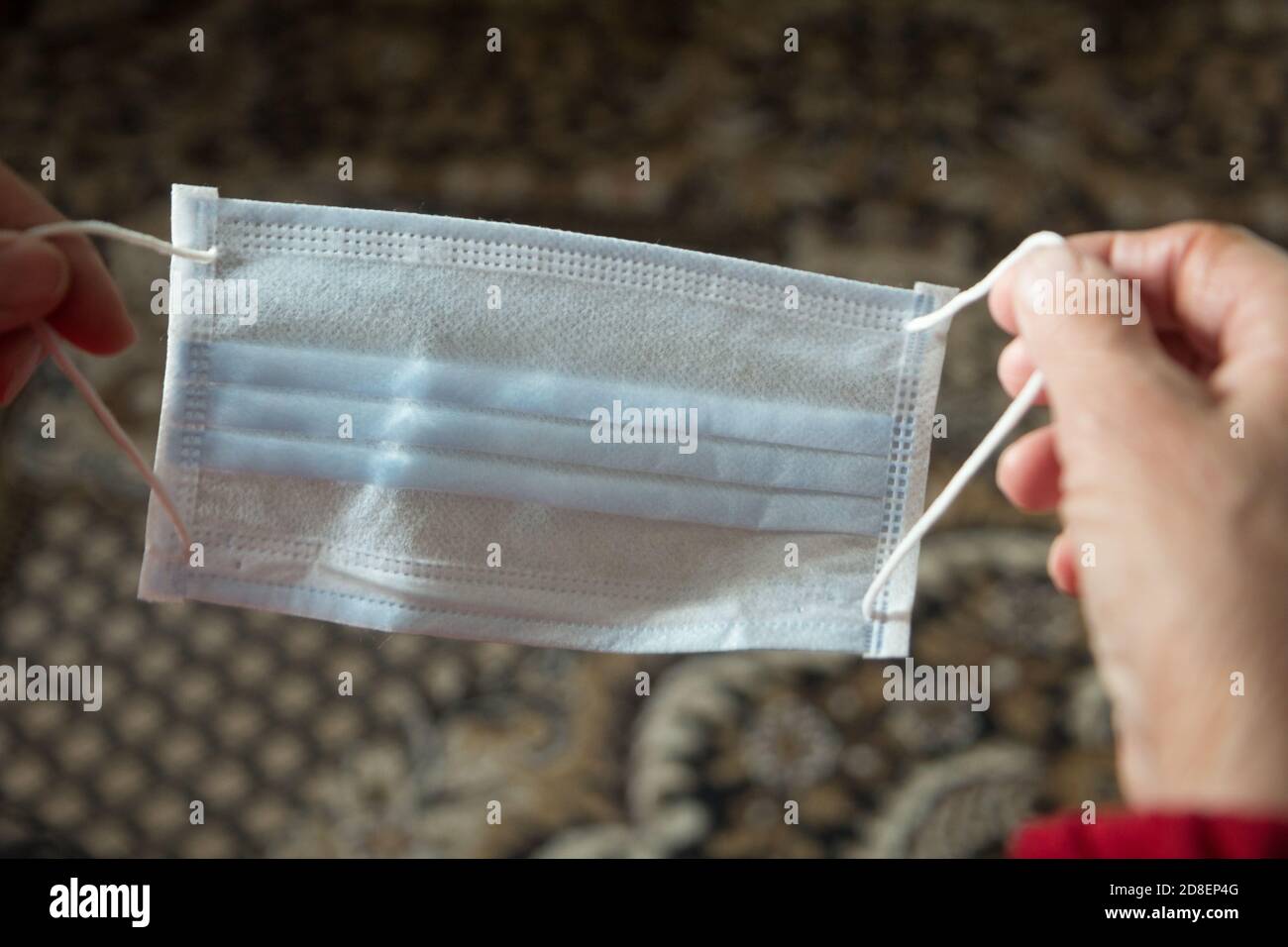 Donna anziana che tiene in mano la maschera facciale Foto Stock