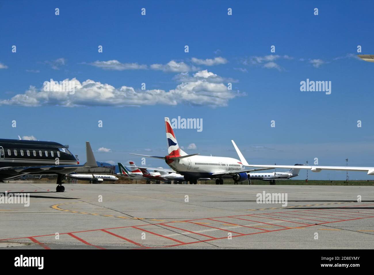 Affollata pista dell'aeroporto di Genova, con diversi aerei parcheggiati, in attesa di salire a bordo dei passeggeri. Cielo blu meraviglioso e giorno di sole. Viaggi e Vacatio Foto Stock